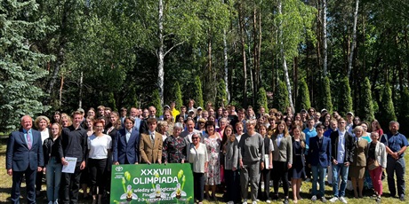 Powiększ grafikę: Uczestnicy, opiekunowie i organizatorzy Olimpiady na tle lasu.