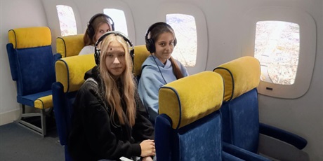 Powiększ grafikę: Trzy uczennice w pociągu. Wszystkie mają słuchawki na uszach.
