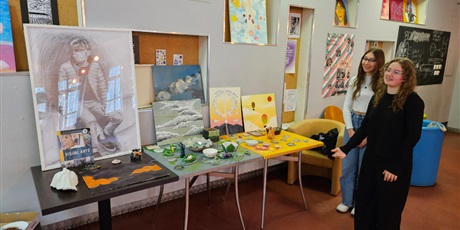 Powiększ grafikę: Uczennice przy ekspozycji prac (plakaty, obrazy, ceramika) z Visual Arts
