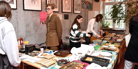 Powiększ grafikę: Uczeń w mundurze wojskowym sprzedaje ciasta w klubie
