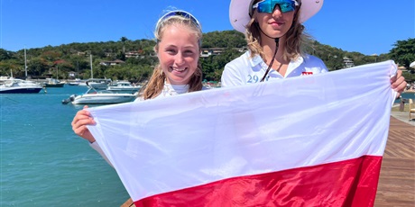 Powiększ grafikę: Dwie uczennice na pomoście trzymają Polską flagę
