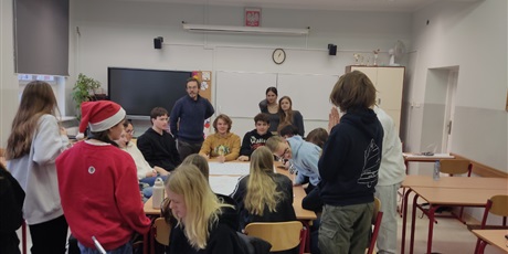 Powiększ grafikę: Grupa uczniów siedząca i stojąca wokół stołu.