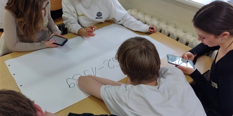 Powiększ grafikę: Grupa czworga uczniów przygotowuje napis na dużym arkuszu papieru.