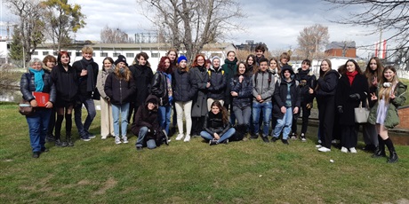 Powiększ grafikę: Zdjęcie grupowe uczestników spaceru (29 uczniów) z panią przewodnik i p. M. Gradolewską na trawniku przy kanale Raduni