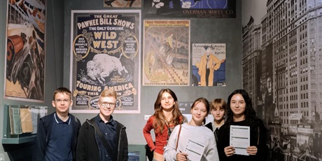 Powiększ grafikę: Grupa uczniów na tle plakatów promujących spektakle